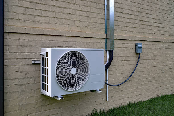Air Conditioner mini split system next to home with painted brick wall and space for text copy
