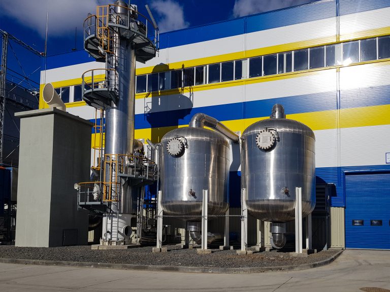 Large industrial HVAC or refrigeration equipment featuring metal pressure vessels, ventilation stacks, and ductwork installed outside a blue and yellow striped commercial building.RetryClaude can make mistakes. Please double-check responses.